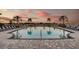Twilight poolside view featuring lounge chairs and palm trees against a backdrop of a colorful sky at sunset at 2559 Driftwood St, Auburndale, FL 33823