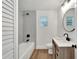 Well-lit bathroom with a shower-tub combo, gray vertical tiles, and a modern vanity with a round mirror at 800 N Church Ave, Mulberry, FL 33860