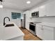 Modern kitchen with white cabinetry, stainless steel appliances, quartz countertops, and hardwood flooring at 800 N Church Ave, Mulberry, FL 33860