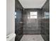 Close-up of modern shower with black tile walls, mosaic tile floor, and brushed gold hardware at 800 N Church Ave, Mulberry, FL 33860