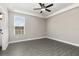 Neutral bedroom boasts tray ceilings, a ceiling fan, a window, and gray wood flooring at 7692 Somersworth Dr, Kissimmee, FL 34747