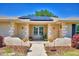 Inviting front porch with charming details, landscaping, hanging flowers, and solar panels on the roof at 53 Paine Dr, Winter Haven, FL 33884