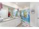 Well-lit bathroom with a double sink vanity, large mirror, and decorative tropical shower curtain at 947 Serchio St, Haines City, FL 33844