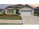 Charming single-Gathering home featuring a two-car garage and inviting front yard with colorful landscaping at 947 Serchio St, Haines City, FL 33844