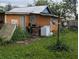 Exterior view of a backyard with an orange house and overgrown lawn with a washing machine at 1529 Indiana St, Orlando, FL 32805