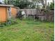 Outdoor shot of a backyard with an overgrown lawn and a dilapidated wooden fence at 1529 Indiana St, Orlando, FL 32805