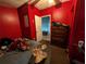 Red bedroom with a dresser, table, and bed filled with personal items and belongings at 1529 Indiana St, Orlando, FL 32805