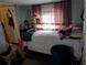 Bedroom with a white bed, striped curtains and some personal affects in a cluttered space at 1529 Indiana St, Orlando, FL 32805