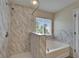 Bright bathroom featuring a separate tub and shower with decorative tile surround and large window for natural light at 2415 Brownwood Dr, Mulberry, FL 33860