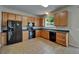 Full kitchen view features wooden cabinets, black appliances, dark countertops, and tiled floors at 2415 Brownwood Dr, Mulberry, FL 33860