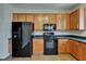 Kitchen view showcases wooden cabinets and black appliances including a refrigerator, oven, and microwave at 2415 Brownwood Dr, Mulberry, FL 33860
