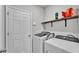 Bright laundry room with modern washer and dryer, white walls, and open shelving at 1859 Carnostie Rd, Winter Haven, FL 33884
