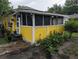 Charming, yellow exterior showcasing a screened-in porch with decorative lighting and landscaping at 730 Citrus St, Orlando, FL 32805