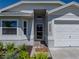 Inviting front entrance with mature landscaping, a Welcome mat, a garage, and a cheerful gray color scheme at 6229 Raven Run, Lakeland, FL 33809