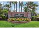 Kingsbridge West brick entrance sign with manicured flower bed and mature palm trees on a sunny day at 917 Keep Way Loop, Oviedo, FL 32765