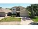 Charming two-story home featuring a stone facade, well-manicured landscaping, and a brick driveway at 1705 Plantation Pointe Dr, Orlando, FL 32824