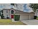 Charming two-story home features a red front door and a spacious three-car garage at 105 Evergreen Dr, Auburndale, FL 33823