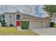 Two-story home featuring a two-car garage, manicured lawn, bright red front door, and neutral exterior color at 105 Evergreen Dr, Auburndale, FL 33823