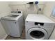 Well-lit laundry room featuring a modern washer and dryer with overhead shelving at 11757 Se 71St Terrace Rd, Belleview, FL 34420