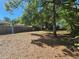 Large backyard featuring mature trees, partial fencing and leaf covered ground at 1960 Hamilton St, Bartow, FL 33830