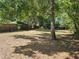 Large backyard featuring mature trees, partial fencing and leaf covered ground at 1960 Hamilton St, Bartow, FL 33830