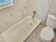 This bathroom features a sleek, white bathtub and toilet complemented by modern, gold-toned fixtures at 1960 Hamilton St, Bartow, FL 33830