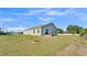 A spacious backyard with green grass, a small patio with seating, and a view of the surrounding neighborhood at 513 Kimbrel Ct, Haines City, FL 33844