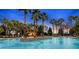 A large swimming pool is surrounded by palm trees, lounge chairs, and blue umbrellas at 8199 Sw 52Nd Lane Rd, Ocala, FL 34481