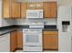 Traditional kitchen with wood cabinets, dark countertops, and white appliances at 50989 Highway 27 # 179, Davenport, FL 33897