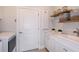 Well-lit laundry room with white cabinets, a sink, decor shelving and a white washer and dryer at 5832 Sw 87Th Ave, Ocala, FL 34481