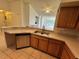 Kitchen featuring stainless steel appliances, wooden cabinets, and a view of the living room at 13103 Mulberry Park Dr # 833, Orlando, FL 32821