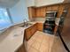 Bright kitchen featuring modern stainless steel appliances, wooden cabinets, and neutral tile flooring at 13103 Mulberry Park Dr # 833, Orlando, FL 32821