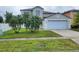 Two-story home featuring a two-car garage, front lawn with palm trees, and neutral-colored exterior at 1416 Aguacate Ct, Orlando, FL 32837