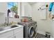 Well-lit laundry room features modern appliances, a large window, a utility sink, and white cabinets at 1239 Roycroft Ave, Kissimmee, FL 34747