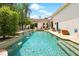 Backyard swimming pool with waterfall feature, bar stools, and steps leading into the pool at 1239 Roycroft Ave, Kissimmee, FL 34747