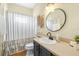 Charming bathroom featuring a dark vanity, round mirror, and decorative accents at 24025 Ranch Rd, Astatula, FL 34705