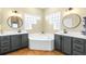 Bathroom featuring dual vanities, a soaking tub, decorative mirrors, and modern fixtures at 24025 Ranch Rd, Astatula, FL 34705