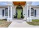 Inviting front entrance with a green door, stately columns, and lush potted plants at 24025 Ranch Rd, Astatula, FL 34705