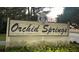 Community sign that reads 'Orchid Springs' set amongst a manicured landscaped entrance at 242 Rosa Blanca, Winter Haven, FL 33884
