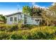 View of a home's rear exterior with overgrown lawn, showing windows and wall-mounted AC units at 117 Sw 3Rd Ave, Mulberry, FL 33860
