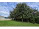 Spacious backyard featuring lush green lawn, mature trees, and a privacy fence under a partly cloudy sky at 13525 Gorgona Isle Dr, Windermere, FL 34786