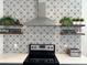 Close-up of stove, tiled backsplash, wooden shelves, and stainless-steel hood at 11578 Ashlin Park Blvd, Windermere, FL 34786