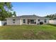 Grassy backyard with fence, seating, grill, and sliding glass doors to patio at 6873 Sw 131St Pl, Ocala, FL 34473