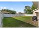 Large backyard with well maintained grass, a white fence and grill with cover at 6873 Sw 131St Pl, Ocala, FL 34473
