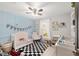 Bedroom featuring blue accent wall, white crib, a black and white checkered rug, and playful decor at 6873 Sw 131St Pl, Ocala, FL 34473