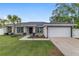 Single Gathering home featuring a two car garage, well-manicured lawn and dark trim at 6873 Sw 131St Pl, Ocala, FL 34473
