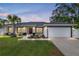 Front of the home showing the lawn, plants, lights, garage and driveway at sunset at 6873 Sw 131St Pl, Ocala, FL 34473