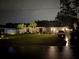 Night shot of the home's front exterior showing the well-lit landscaping and driveway at 6873 Sw 131St Pl, Ocala, FL 34473