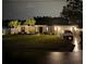 Charming single-story home with manicured lawn, palm trees, a white fence, and a well-lit driveway at night at 6873 Sw 131St Pl, Ocala, FL 34473