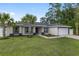 Charming home featuring a lush green lawn, mature palm trees, and a convenient two-car garage at 6873 Sw 131St Pl, Ocala, FL 34473